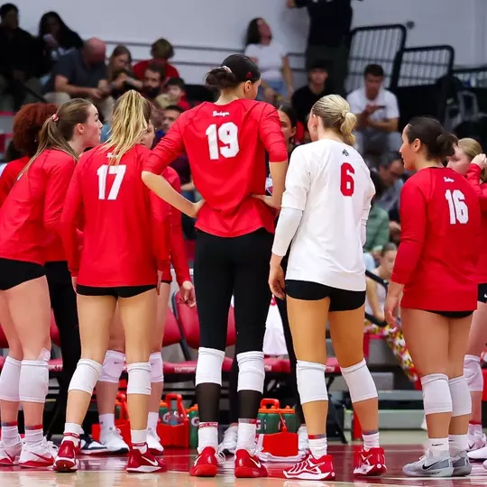 Ohio State Buckeyes volleyball team gathered along the sideline in scarlet warmups before a home match
