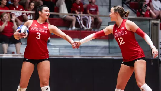 Indiana volleyball players number 3 and 12 shaking hands before a serve in Wilkinson Hall