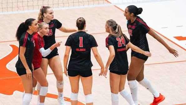 Wisconsin volleyball teammates in black jerseys celebrating a point together during an NCAA Tournament match
