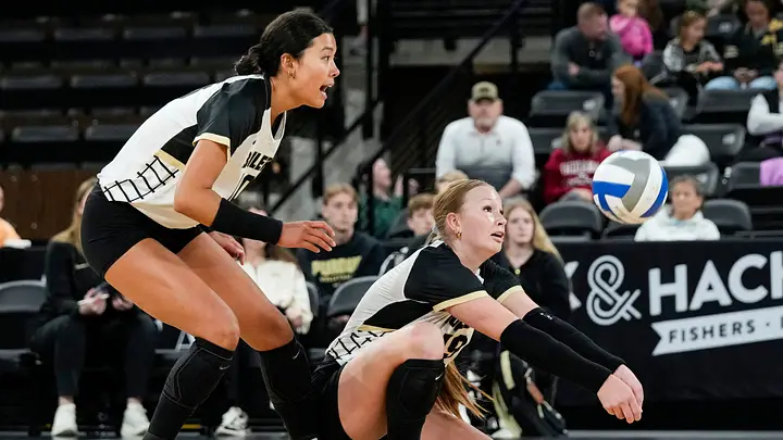 Purdue volleyball defender diving for a dig while a teammate reacts during a Big Ten match