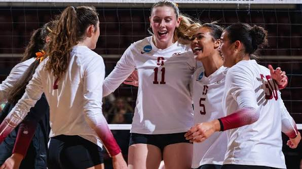 Stanford Cardinal volleyball players celebrating a point during an NCAA Tournament match at Maples Pavilion