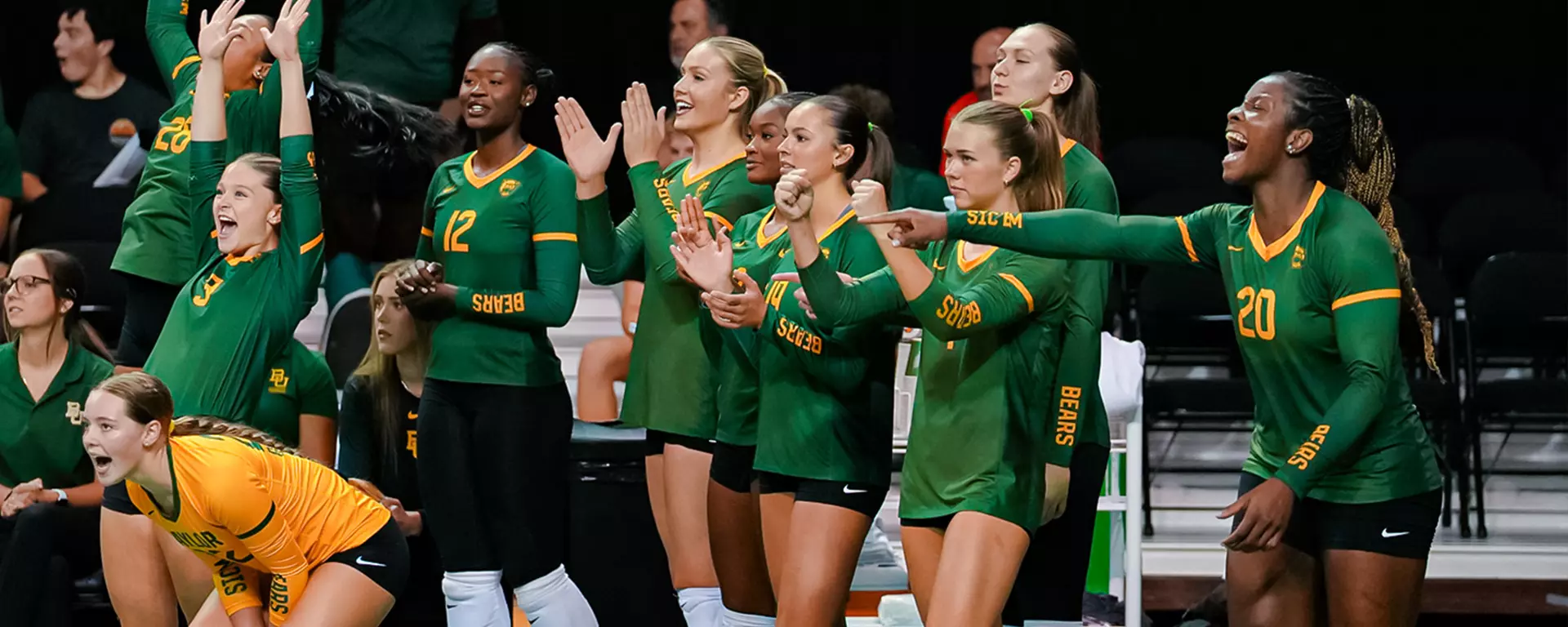 Baylor volleyball players in green jerseys cheering from the bench during a 2026 season match at the Ferrell Center