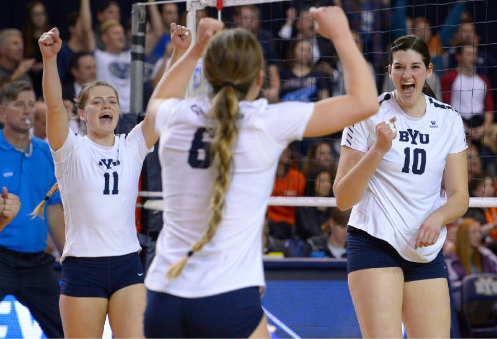 BYU women's volleyball teammates raising fists at the net after winning a rally