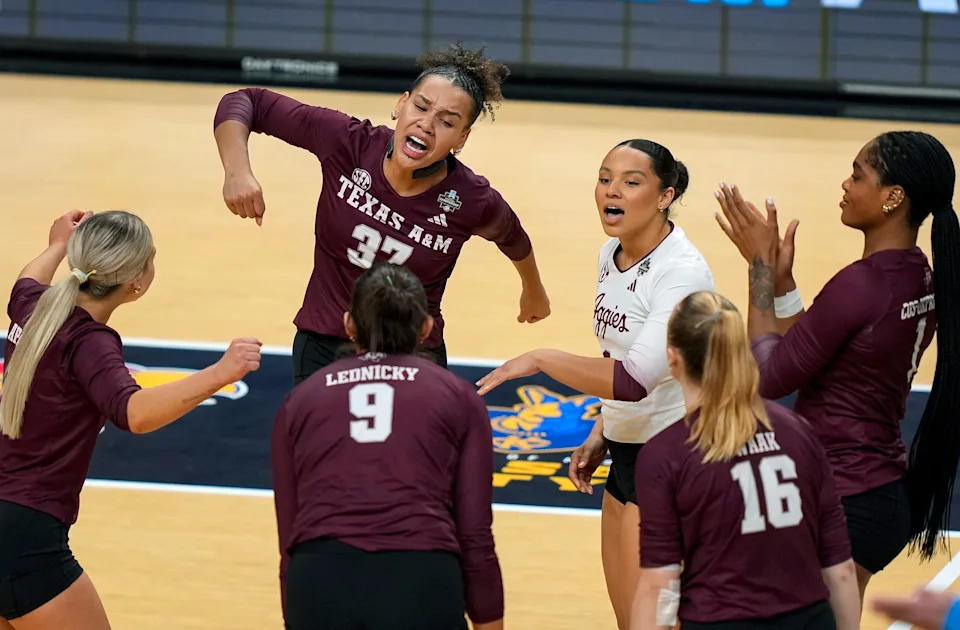 Texas A&M Aggies volleyball players in maroon uniforms celebrating a point at Reed Arena