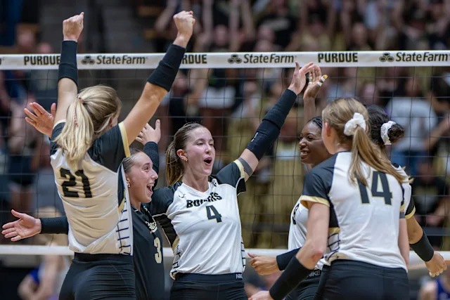 Purdue Boilermakers volleyball teammates raising their arms in celebration after winning a rally