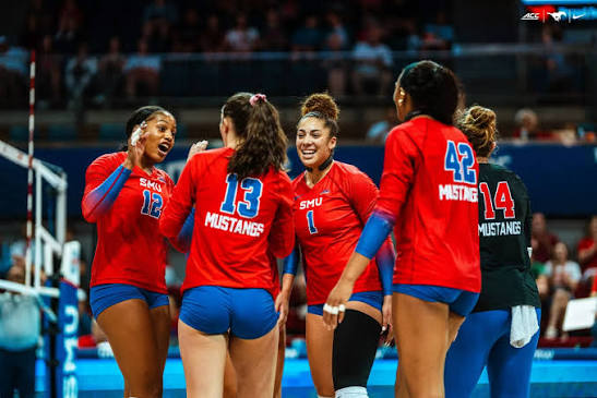 SMU Mustangs volleyball players in red jerseys regrouping at the net after a rally