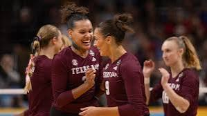 Texas A&M volleyball teammates gathering at the net after winning a long rally