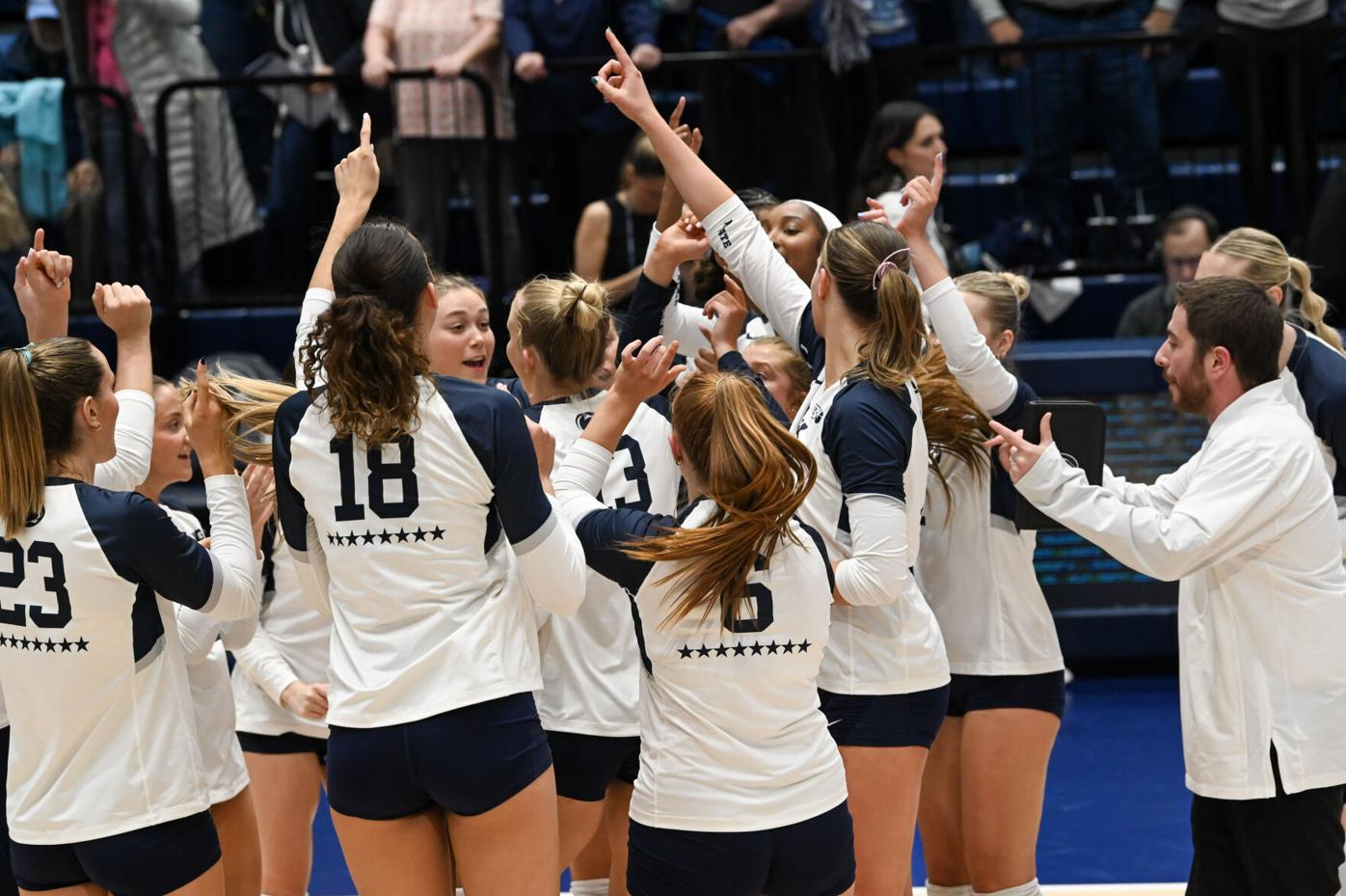 Penn State Nittany Lions volleyball team huddling with fingers raised after a home win