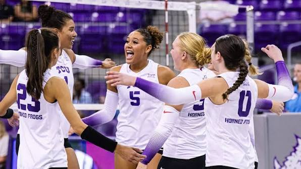 TCU Horned Frogs volleyball teammates celebrating together in white uniforms at Schollmaier Arena
