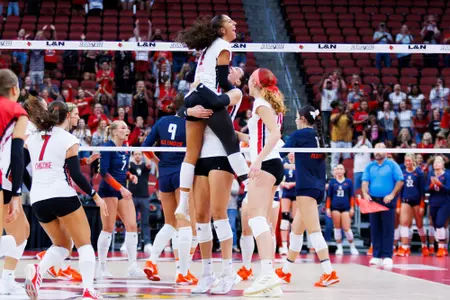 Louisville volleyball players lifting a teammate in celebration at the L&N Federal Credit Union Arena