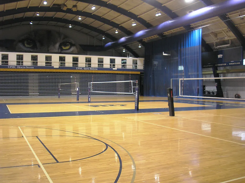 The indoor courts and net inside Pitt’s Fitzgerald Field House, with seating along the sides.