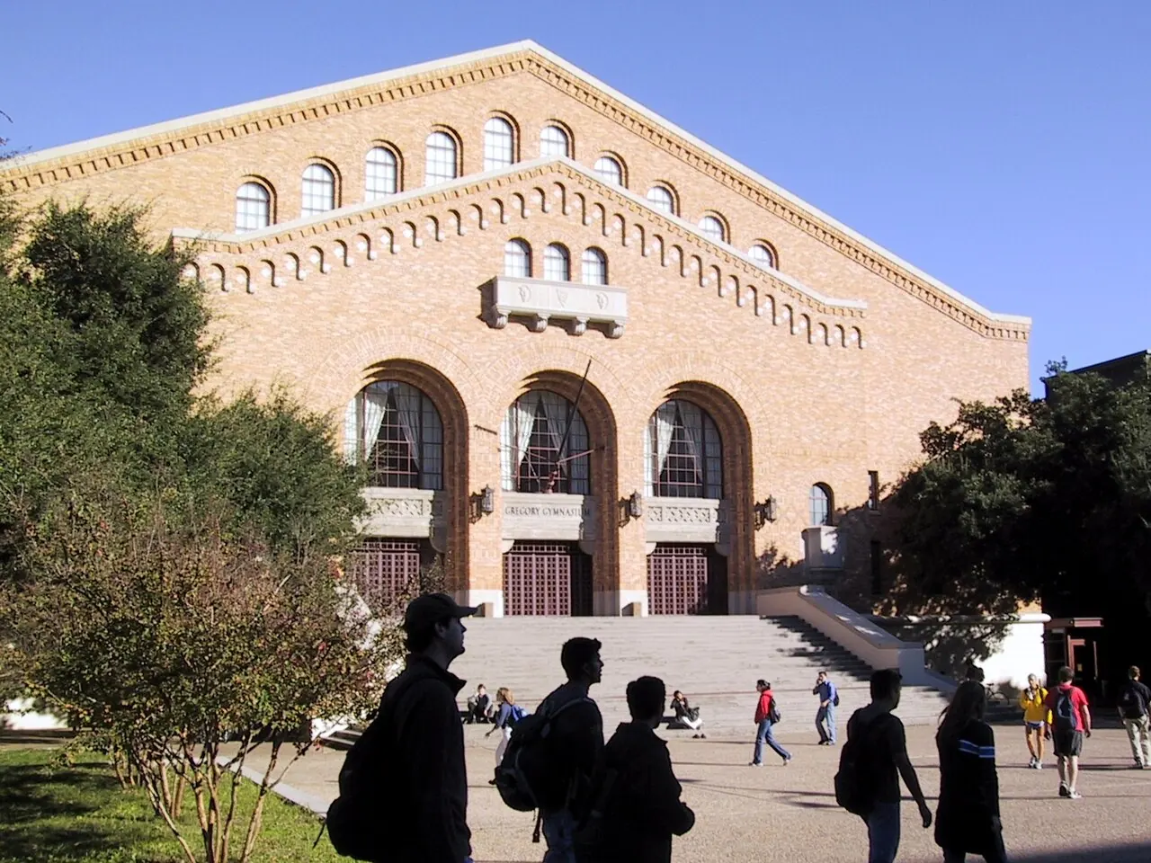 Students walking past the arched entrance of Gregory Gym at the University of Texas at Austin.