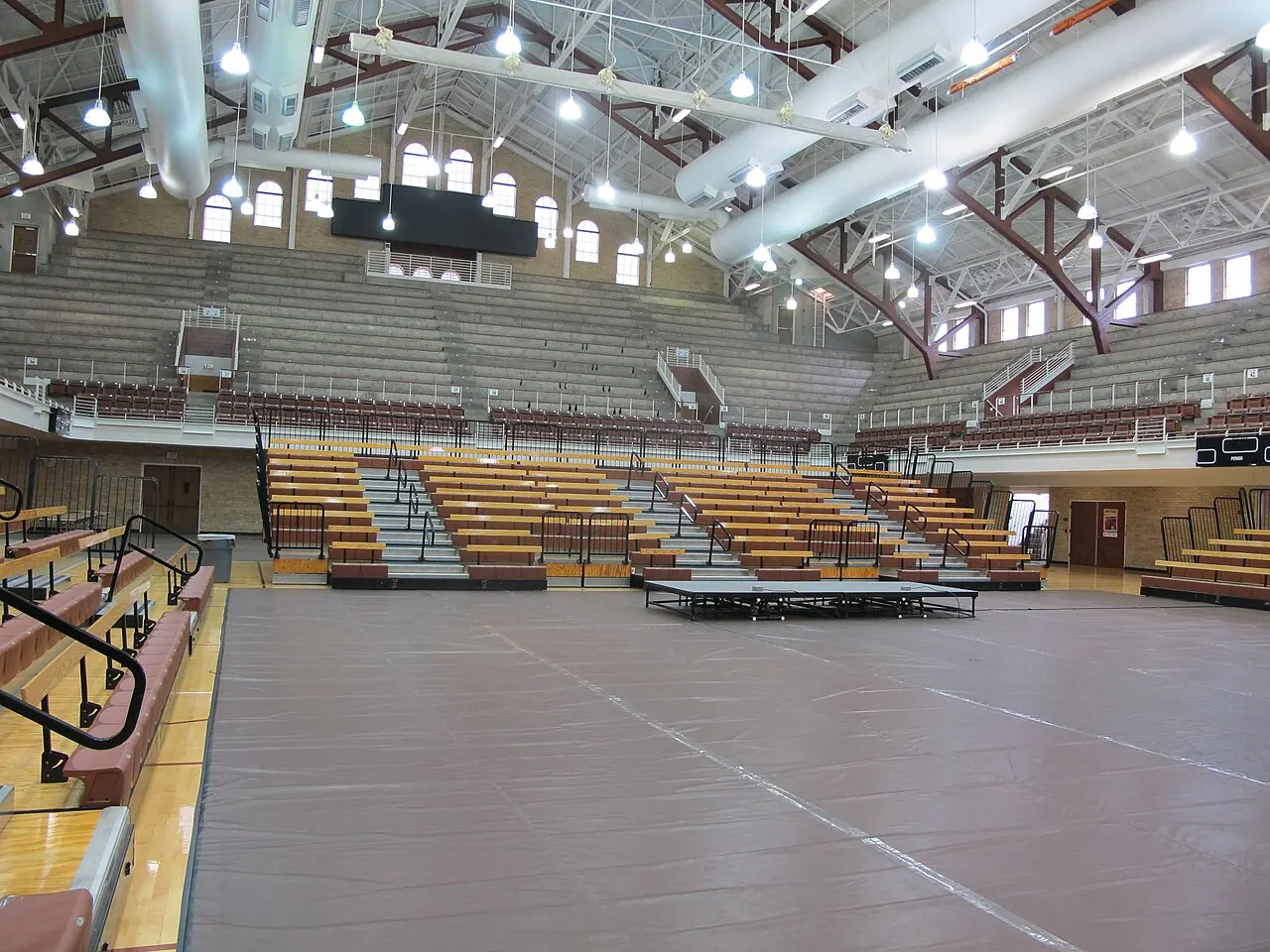 Interior of Gregory Gym with tiered orange seating and the open playing floor.