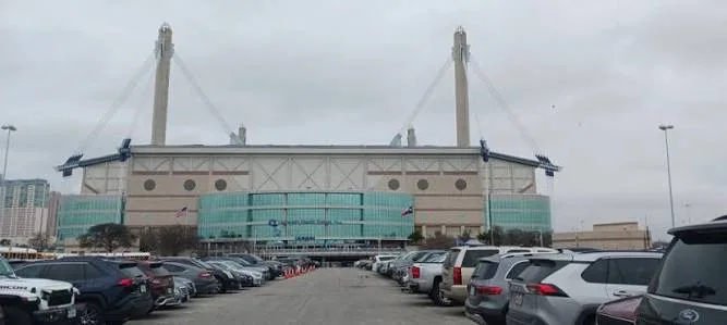 Cars parked in rows outside the Alamodome beneath an overcast sky