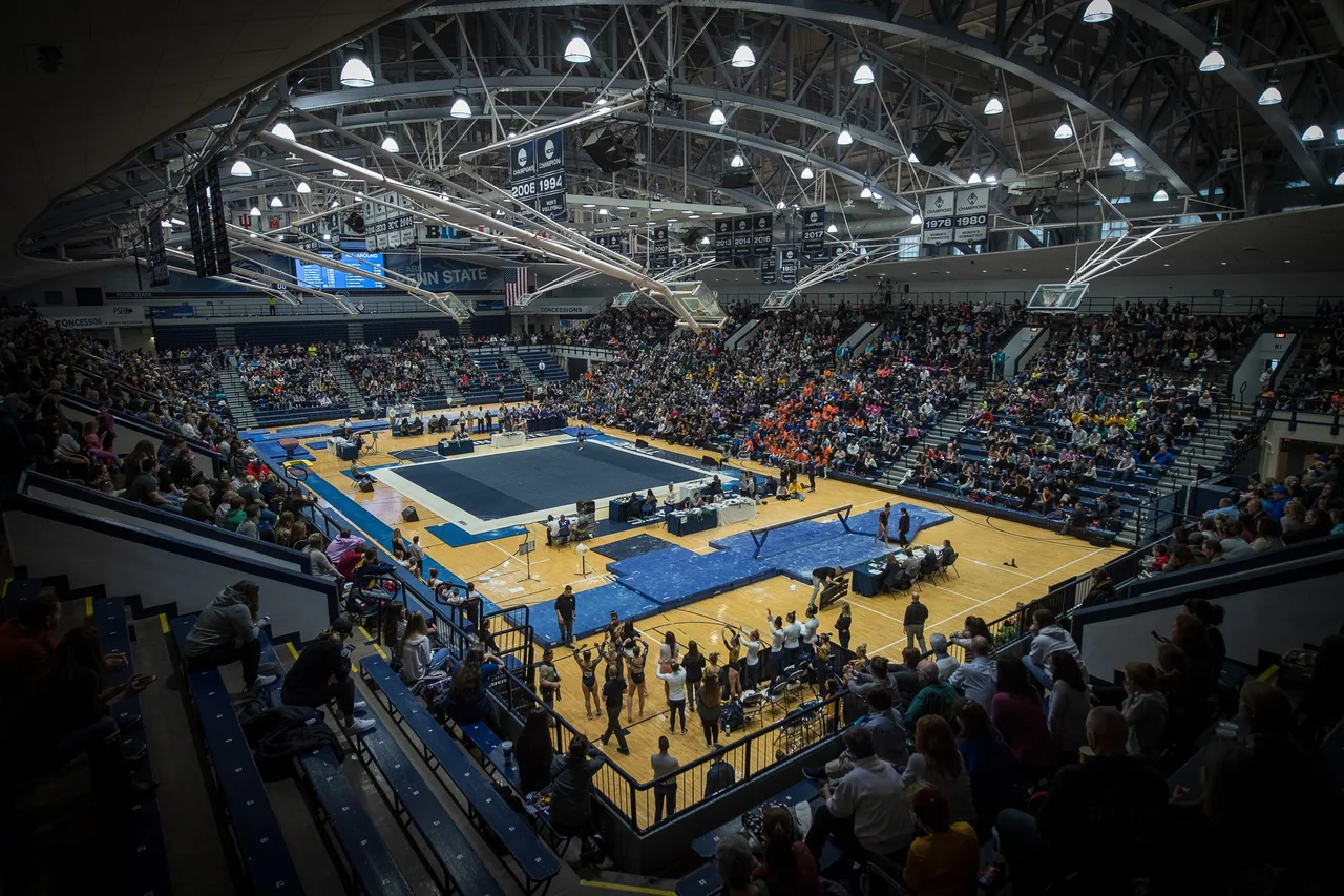 Spectators surrounding gymnastics apparatus on the floor of Penn State Rec Hall