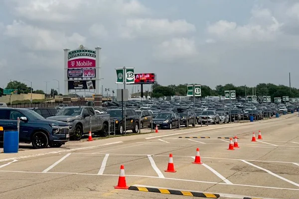 Rows of parked vehicles, numbered aisle signs and traffic cones in a large outdoor parking lot